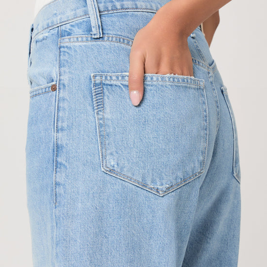 Light blue jeans with a brand logo on a plain background from Paige