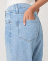 Light blue jeans with a brand logo on a plain background from Paige