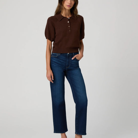 Woman wearing a brown polo shirt and blue jeans on a white background