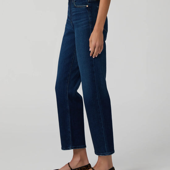 Person wearing dark blue jeans with a plain background