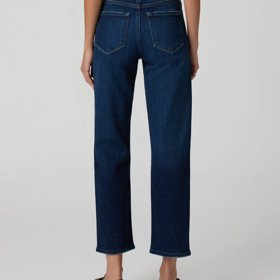 Person wearing dark blue jeans on a plain background