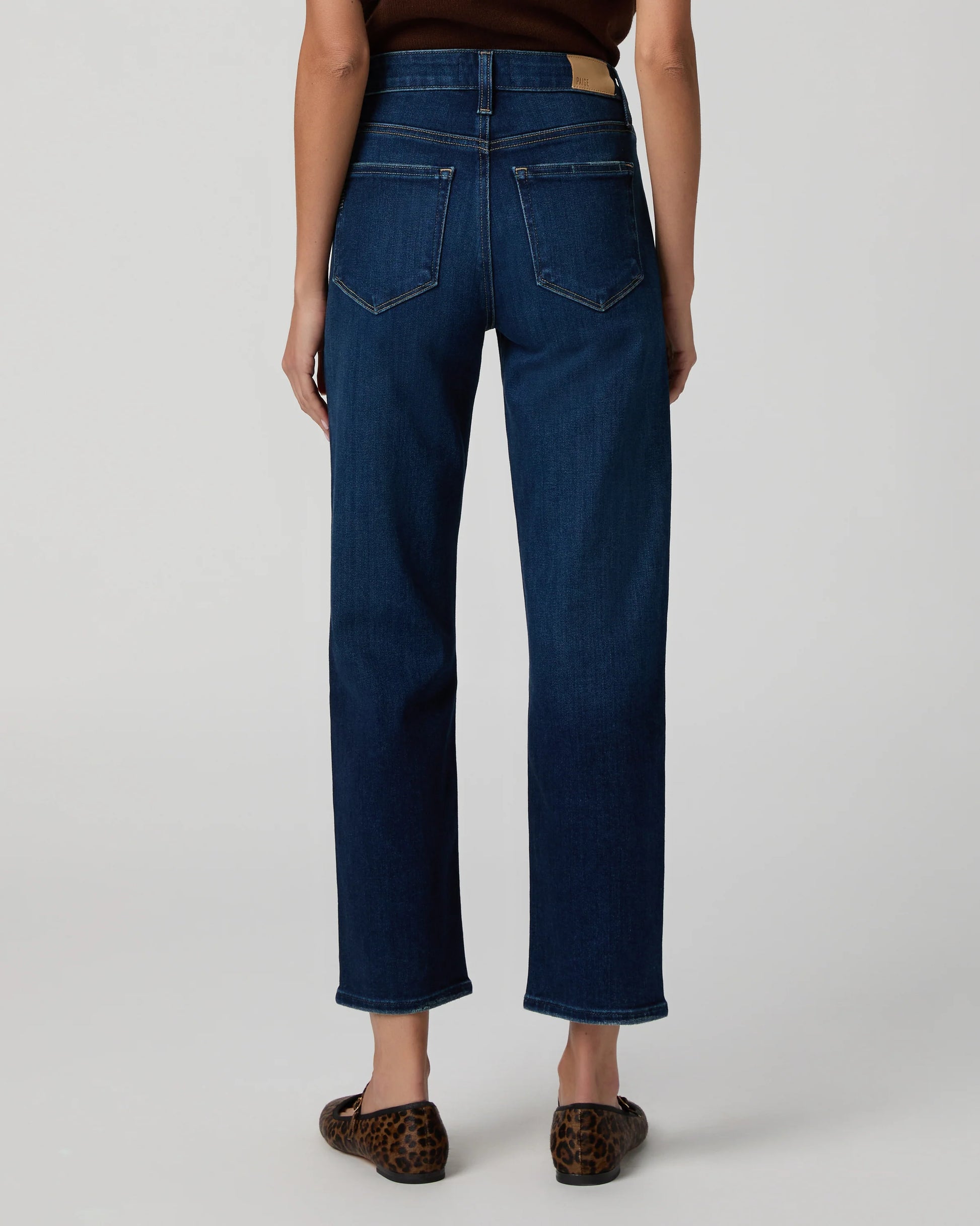 Person wearing dark blue jeans on a plain background