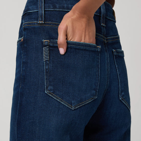 Person wearing blue jeans with a neutral background