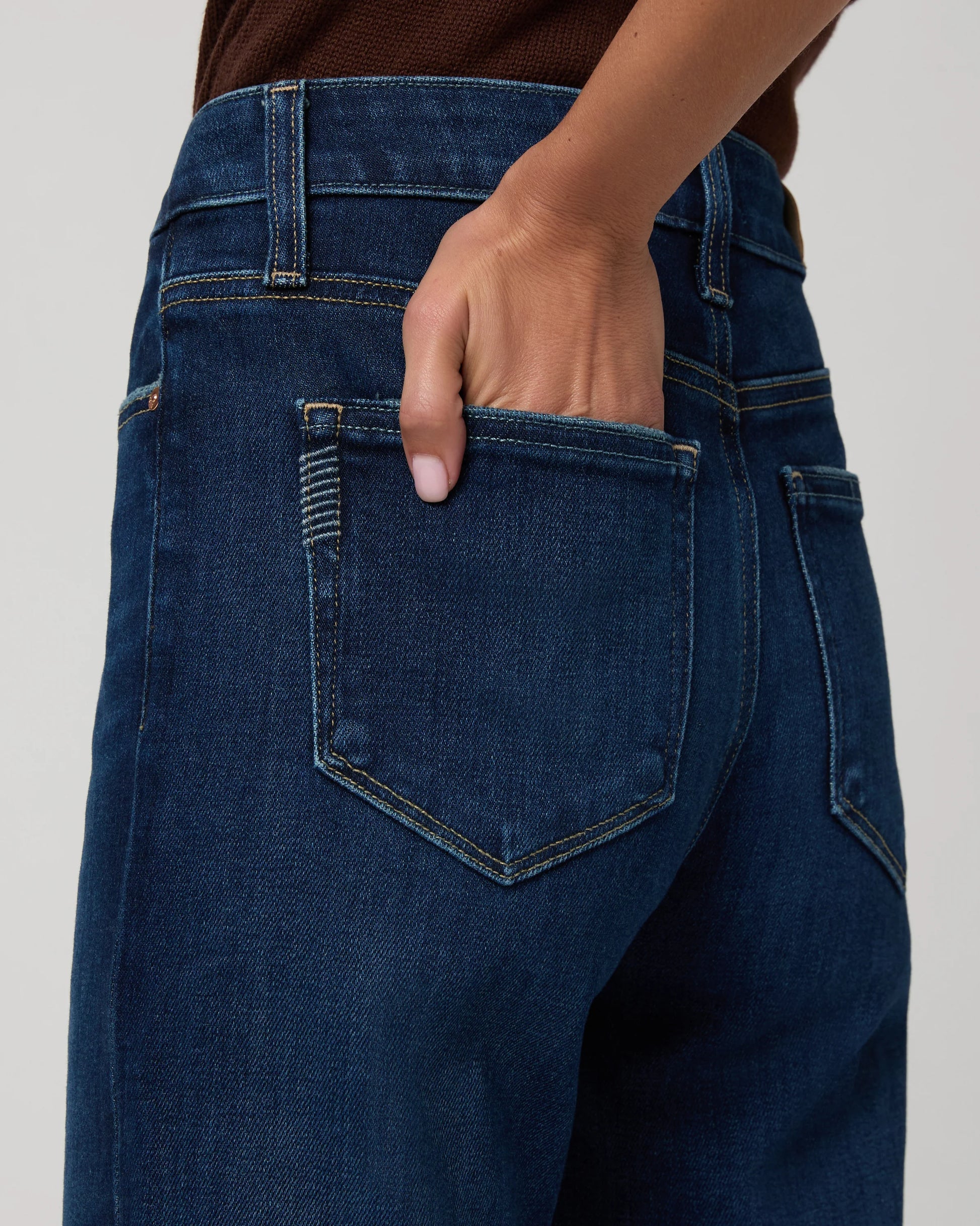 Person wearing blue jeans with a neutral background