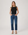 Woman wearing a black top and blue jeans By Paige on a white background