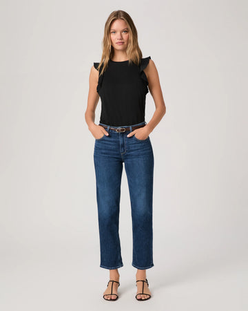 Woman wearing a black top and blue jeans By Paige on a white background