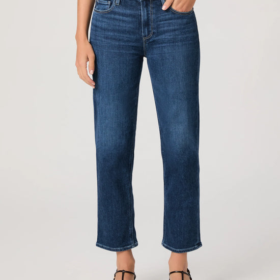 Person wearing blue jeans by paige on a plain background
