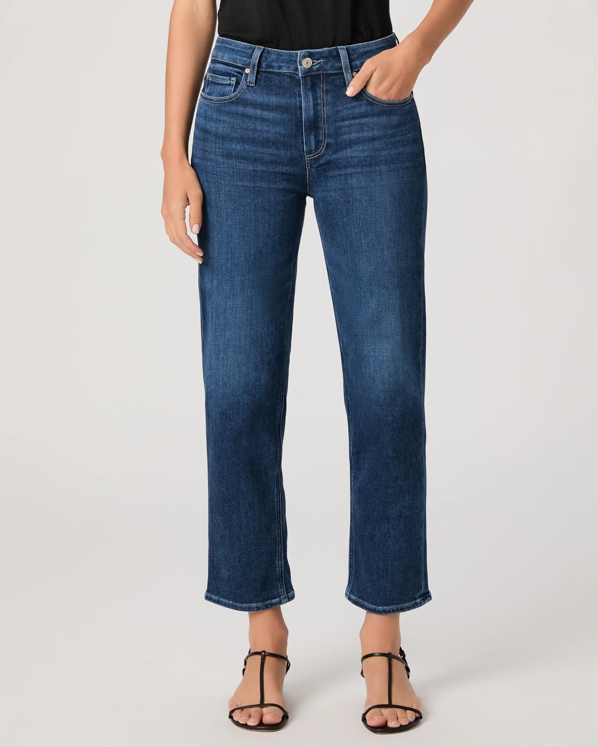 Person wearing blue jeans by paige on a plain background
