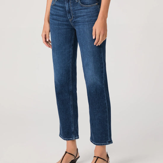 Person wearing blue jeans by paige on a plain background side view