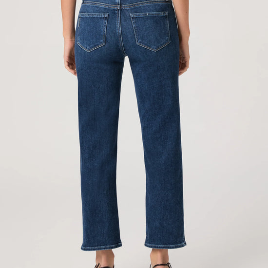 Person wearing blue jeans by paige on a plain background rear view
