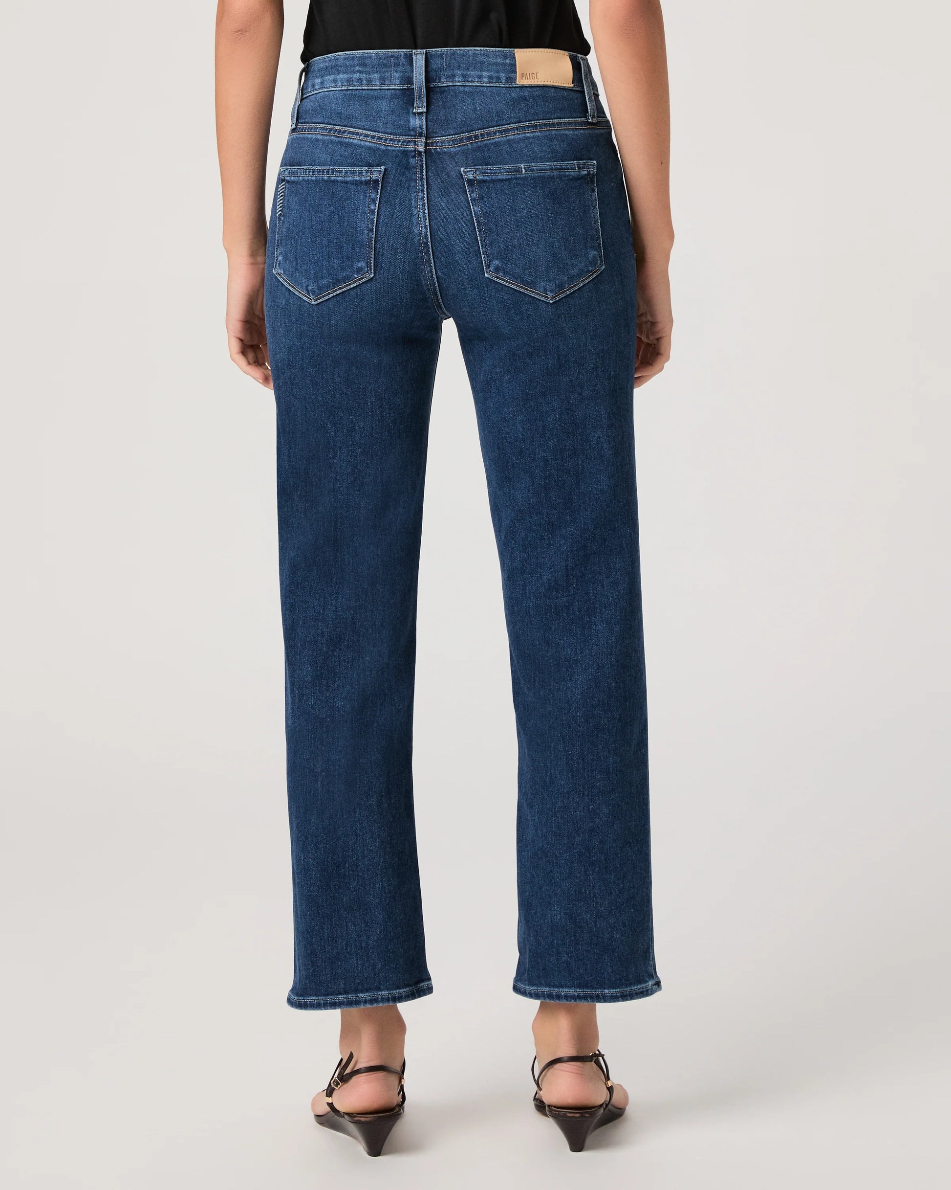 Person wearing blue jeans by paige on a plain background rear view