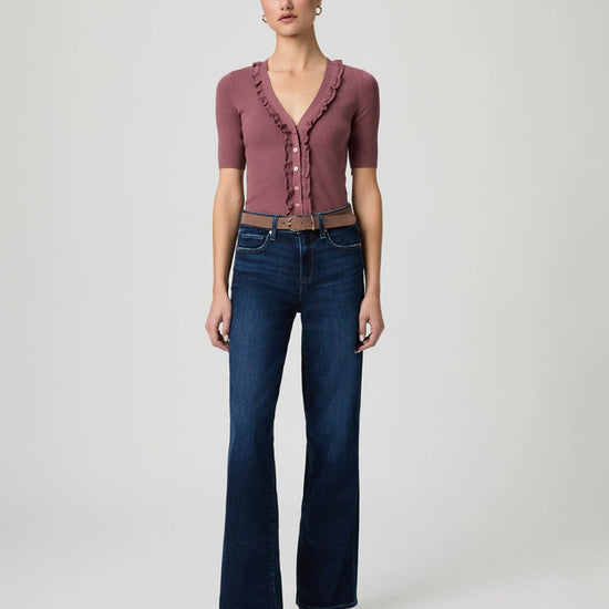 Woman wearing a maroon top and blue jeans on a white background from Paige