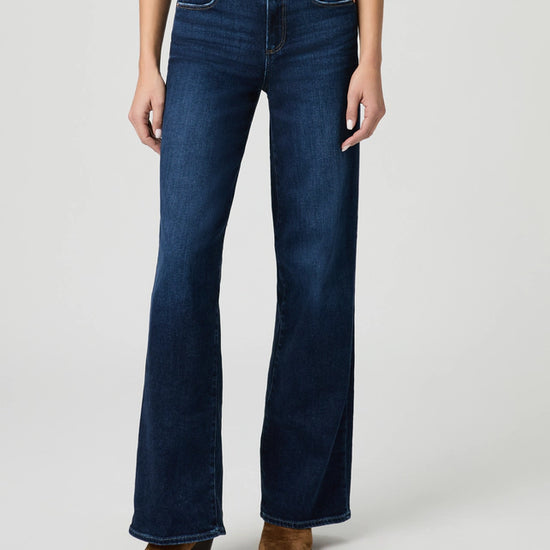 Person wearing dark blue jeans on a light gray background from paige