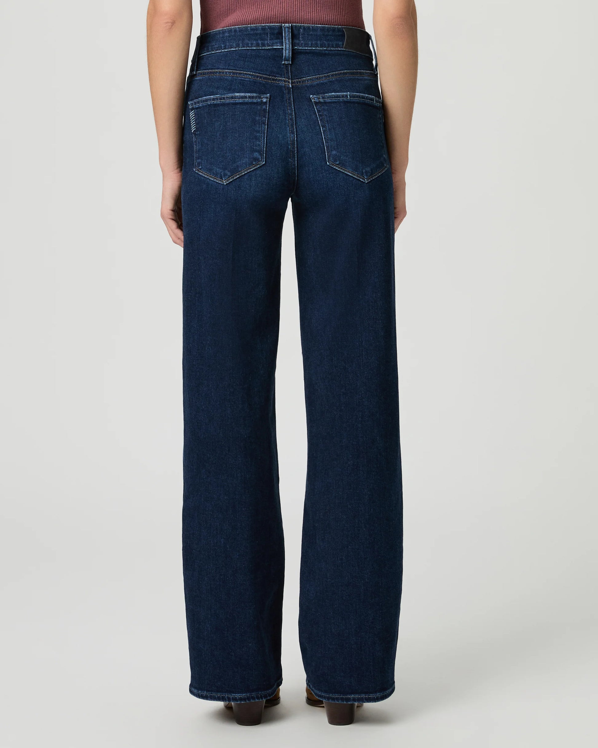 Person wearing blue jeans on a plain background rear view from paige