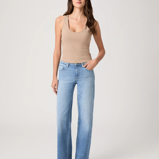 Woman wearing a beige tank top and light blue jeans from Paige on a white background