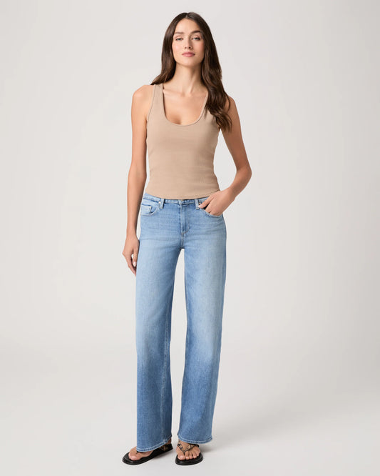 Woman wearing a beige tank top and light blue jeans from Paige on a white background