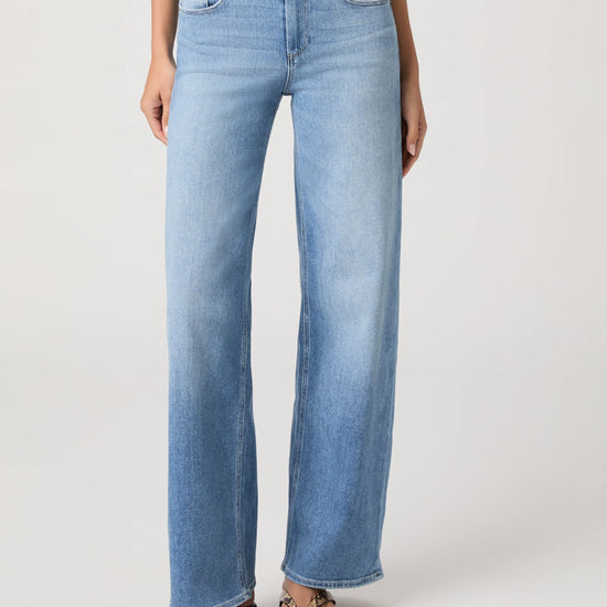 Woman wearing light blue jeans from Paige on a white background