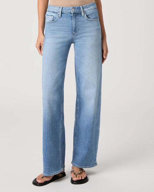 Woman wearing light blue jeans from Paige on a white background