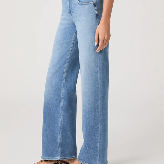 Woman wearing light blue jeans from Paige on a white background side view