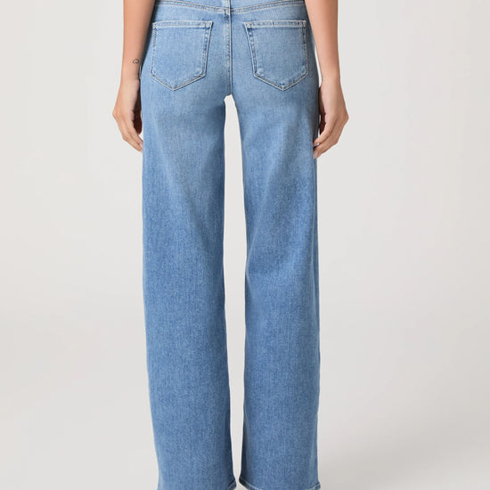 Woman wearing light blue jeans from Paige on a white background rear view
