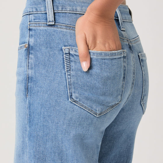 Woman wearing light blue jeans from Paige on a white background close up of pocket