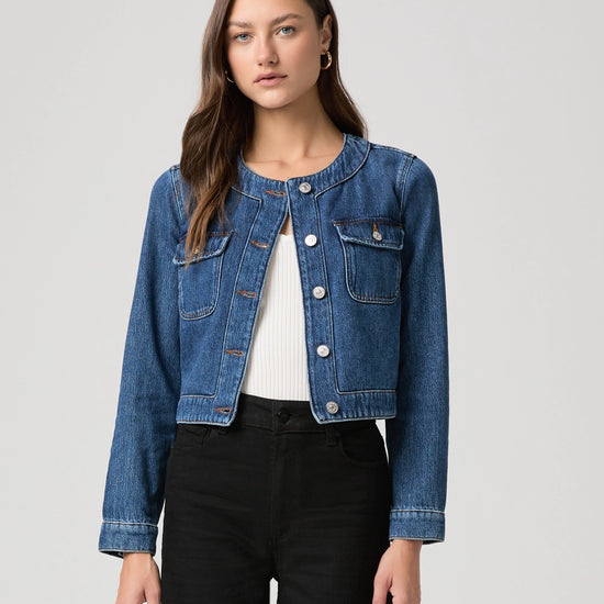 round neck dark blue denim jacket with silver buttons, 2 flap buttoned pockets and cropped fit model shot