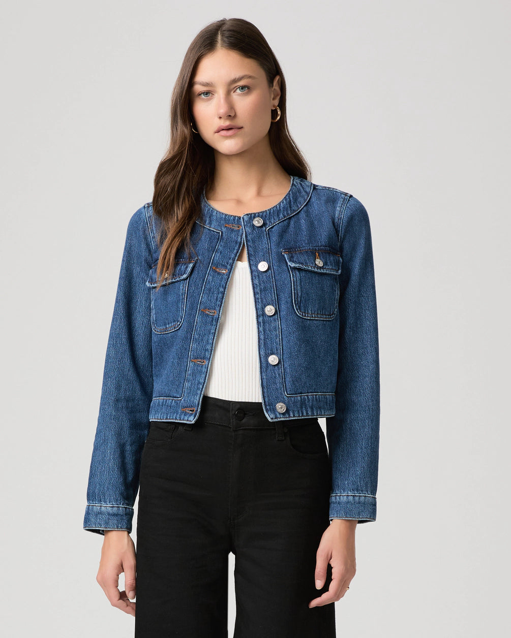 round neck dark blue denim jacket with silver buttons, 2 flap buttoned pockets and cropped fit model shot