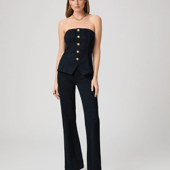 Woman wearing a denim strapless top with gold buttons and denim trousers from Paige