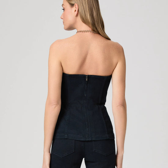 Woman wearing a denim strapless top and pants on a plain background rear view