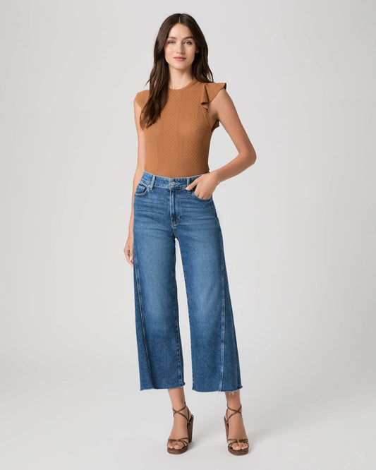 Woman wearing paige blue jeans and a brown top on a white background