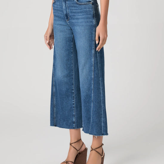 person wearing blue paige jeans on a white background side view