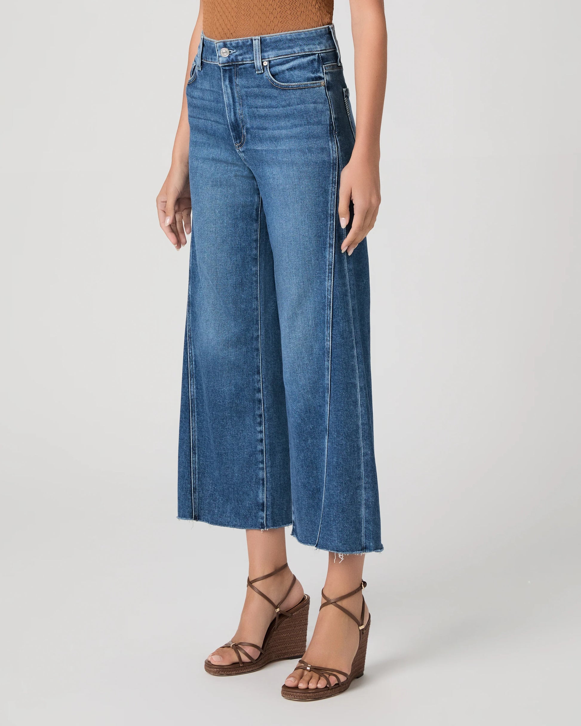 person wearing blue paige jeans on a white background side view