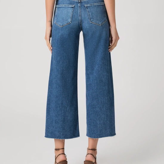person wearing blue paige jeans on a white background rear view