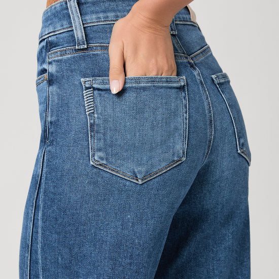 person wearing blue paige jeans on a white background close up 