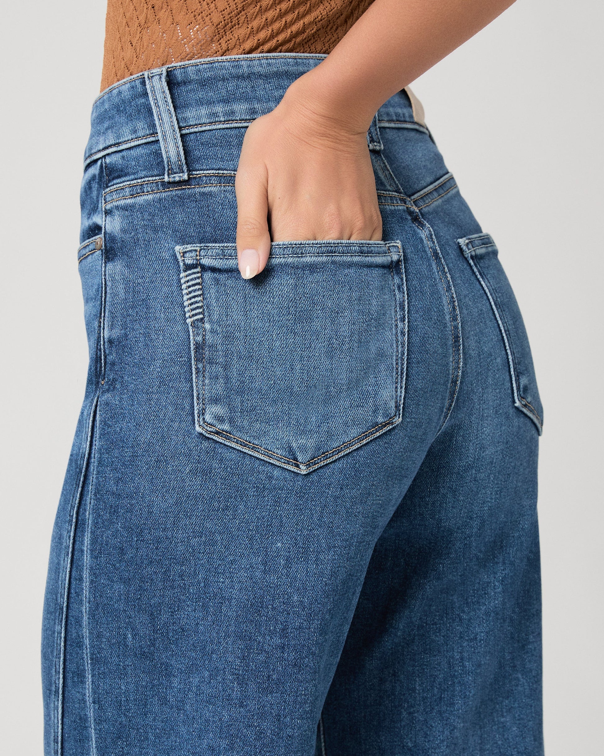 person wearing blue paige jeans on a white background close up 