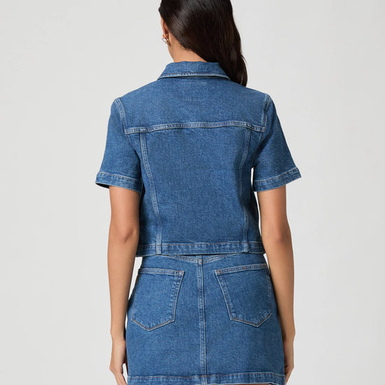 Woman wearing a blue denim dress against a white background