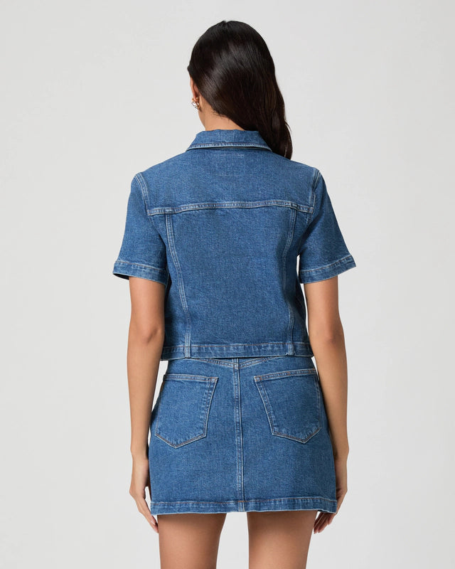 Woman wearing a blue denim dress against a white background
