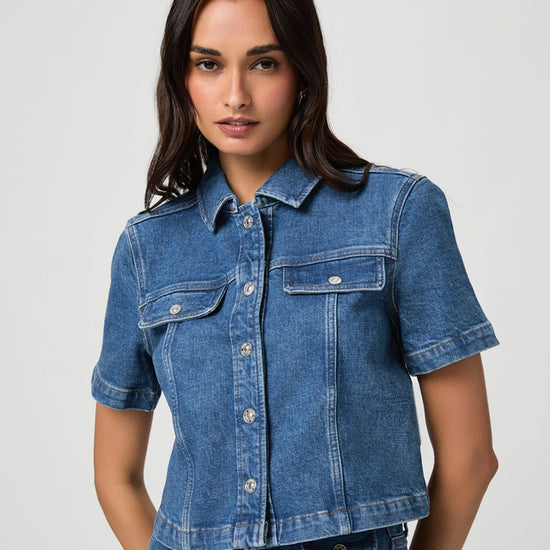 Woman wearing a blue denim shirt against a plain background