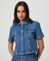 Woman wearing a blue denim shirt against a plain background