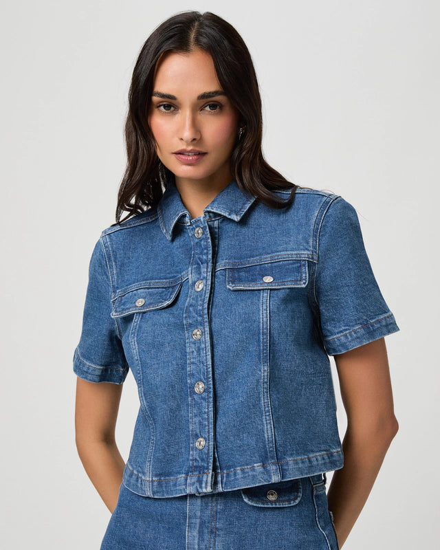 Woman wearing a blue denim shirt against a plain background