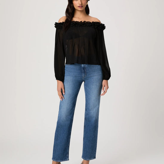 Woman wearing a black off-shoulder top and blue jeans on a white background