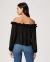 Woman wearing a black off-shoulder top and blue jeans on a plain background