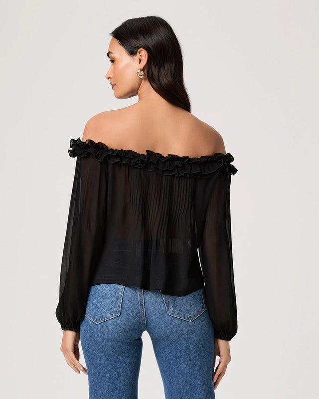 Woman wearing a black off-shoulder top and blue jeans on a plain background
