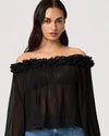 Woman wearing a black off-shoulder top with ruffled details on a white background