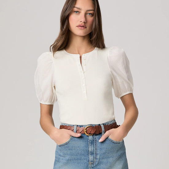 Woman wearing a white blouse and blue jeans on a plain background