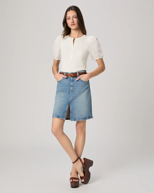 Woman wearing a white blouse and denim skirt on a plain background