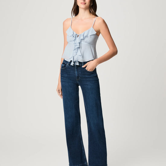 Woman wearing a light blue top and dark blue jeans on a white background