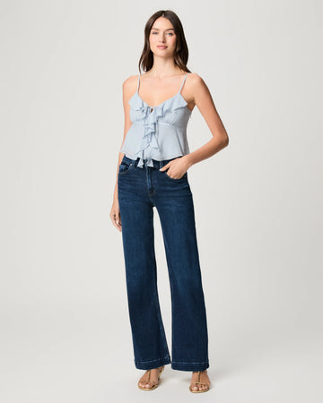 Woman wearing a light blue top and dark blue jeans on a white background