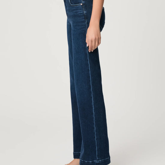 Person wearing dark blue jeans on a white background