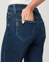 Close-up of blue jeans with a hand in the pocket against a neutral background